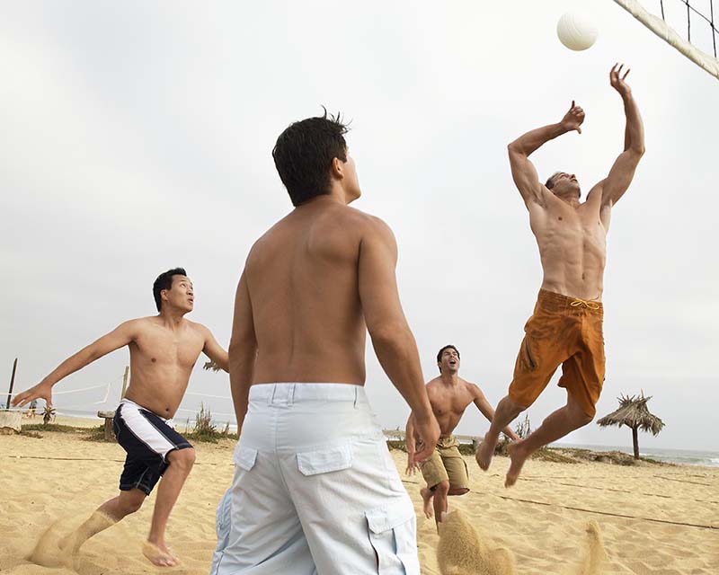 A body contouring patient plays beach volleyball with other attractive men.